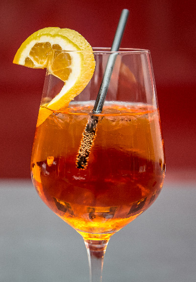 Glass with orange slice, straw and carbonated drink with ice